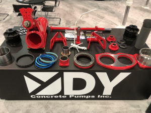 multiple concrete pump parts from DY Concrete Pumps on a table at trade show