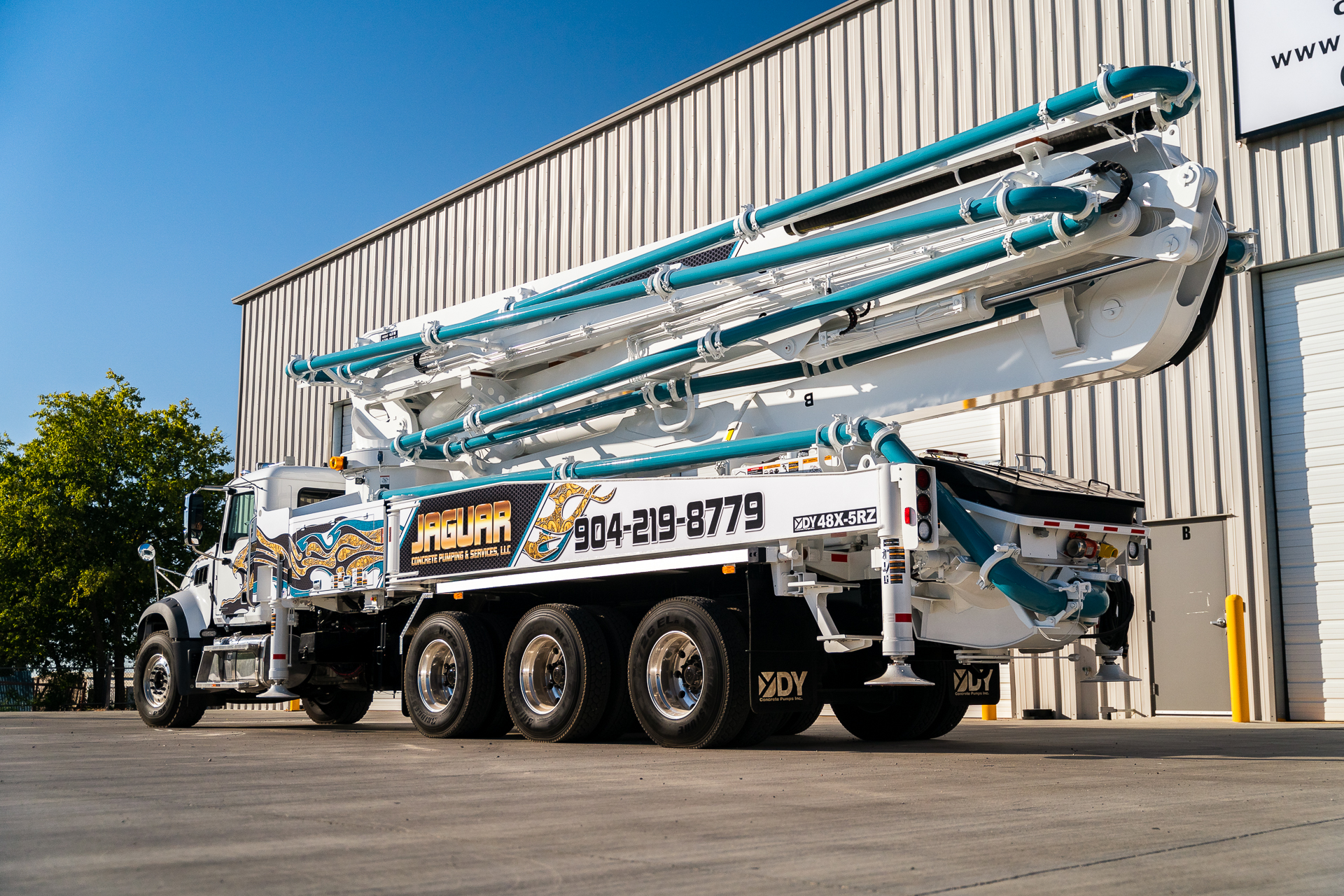 A new DY 48X-5RZ truck-mounted concrete boom pump for Jaguar Concrete Pumping, photographed in the front yard of DY Concrete Pumps’ Texas headquarters.