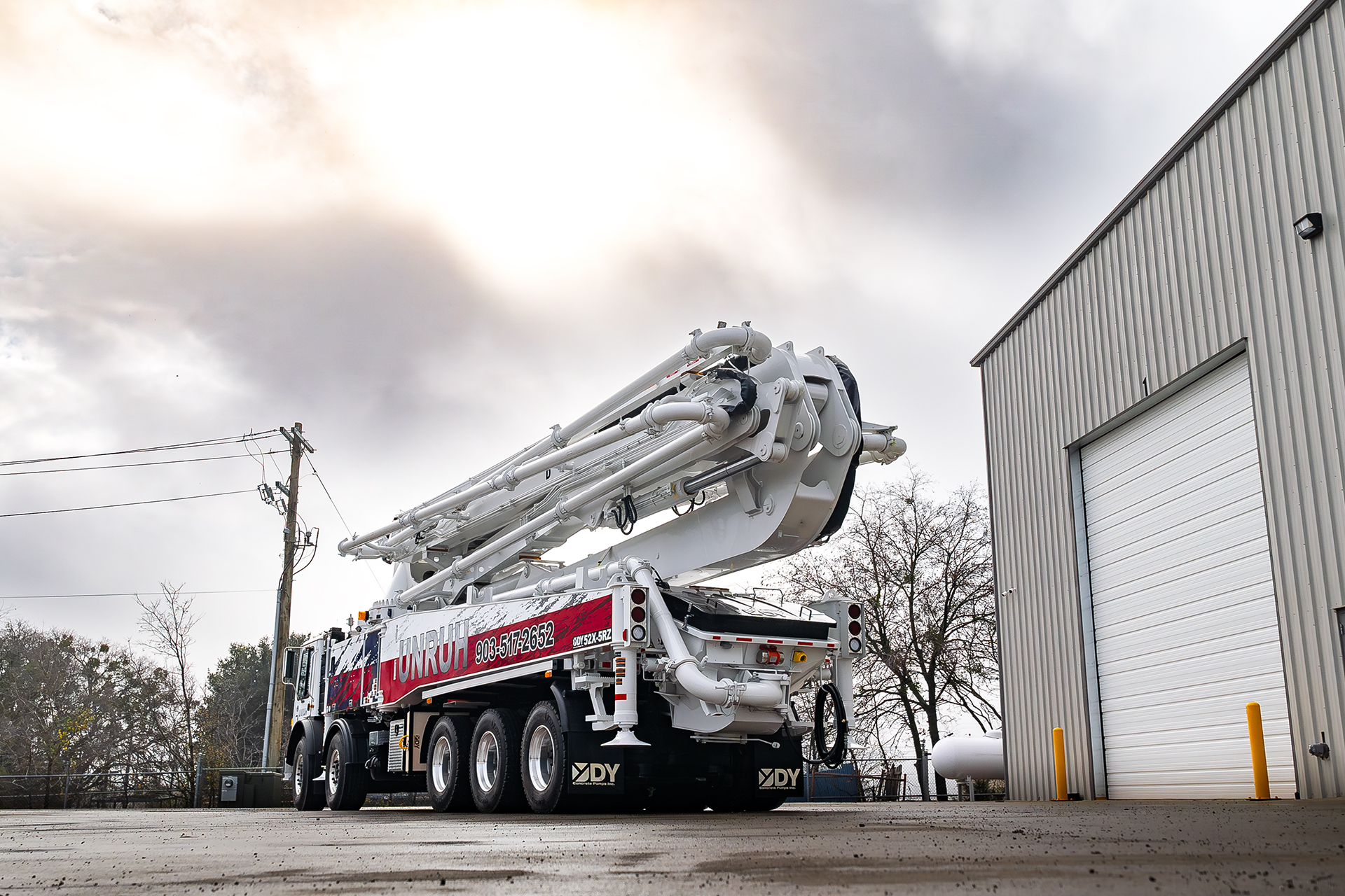 A new DY 52X-5RZ truck-mounted concrete boom pump for Unruh Concrete Pumping, photographed in the front yard of DY Concrete Pumps’ Texas headquarters.