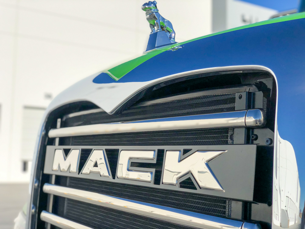 Mack name and figurine on the front of a lime green DY concrete pump