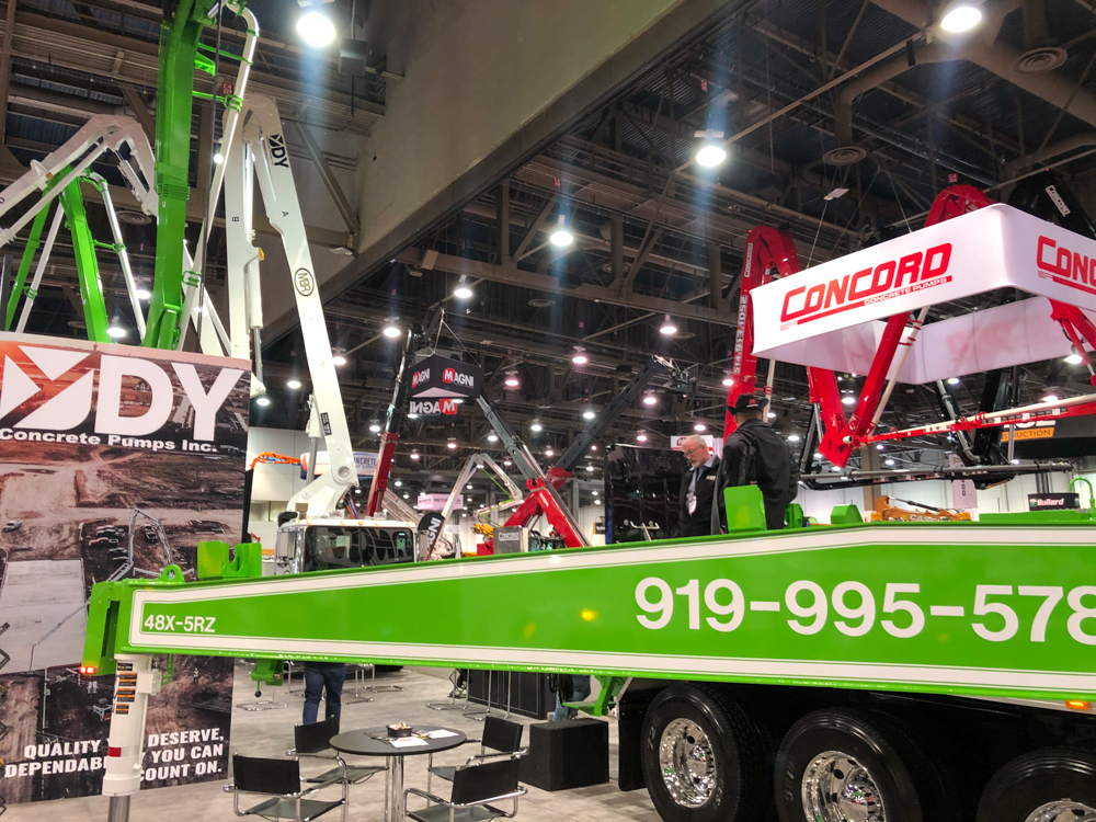 green 48X-5RZ boom pump and DY Concrete Pumps Inc. display inside the WOC event
